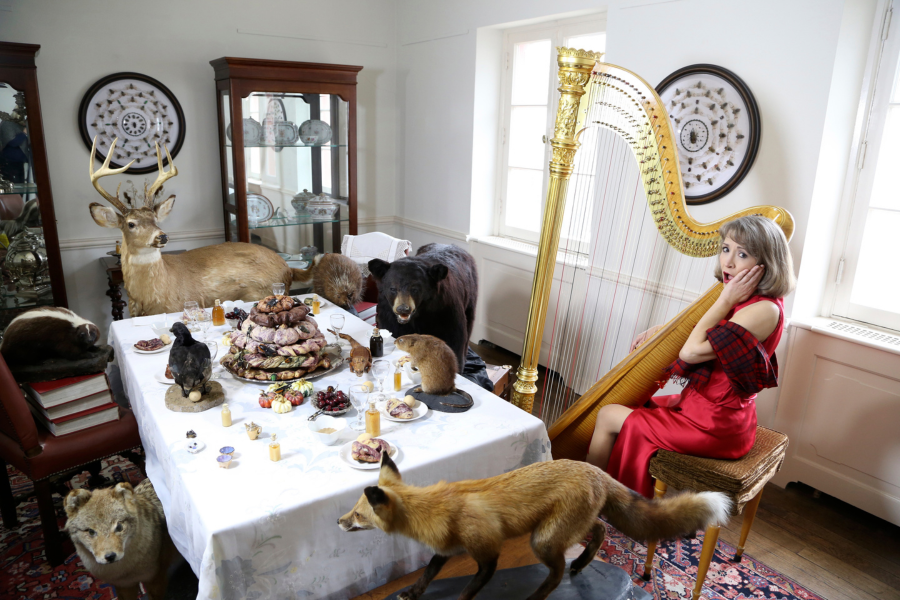 Ann with animals Ann Lobotzke feigns surprise while sitting at a table with her harp surrounded by taxidermy animals.