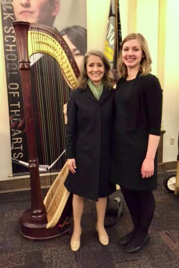 Ann with student Ann Lobotzke stands in front of a harp with a student.