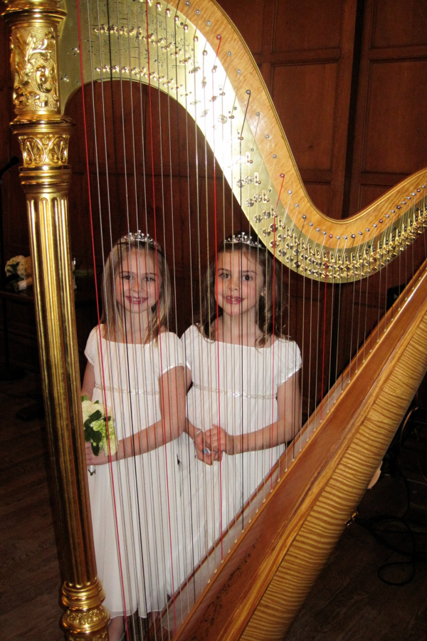 Flower Girls Two flower girls stand behind the strings of a harp.